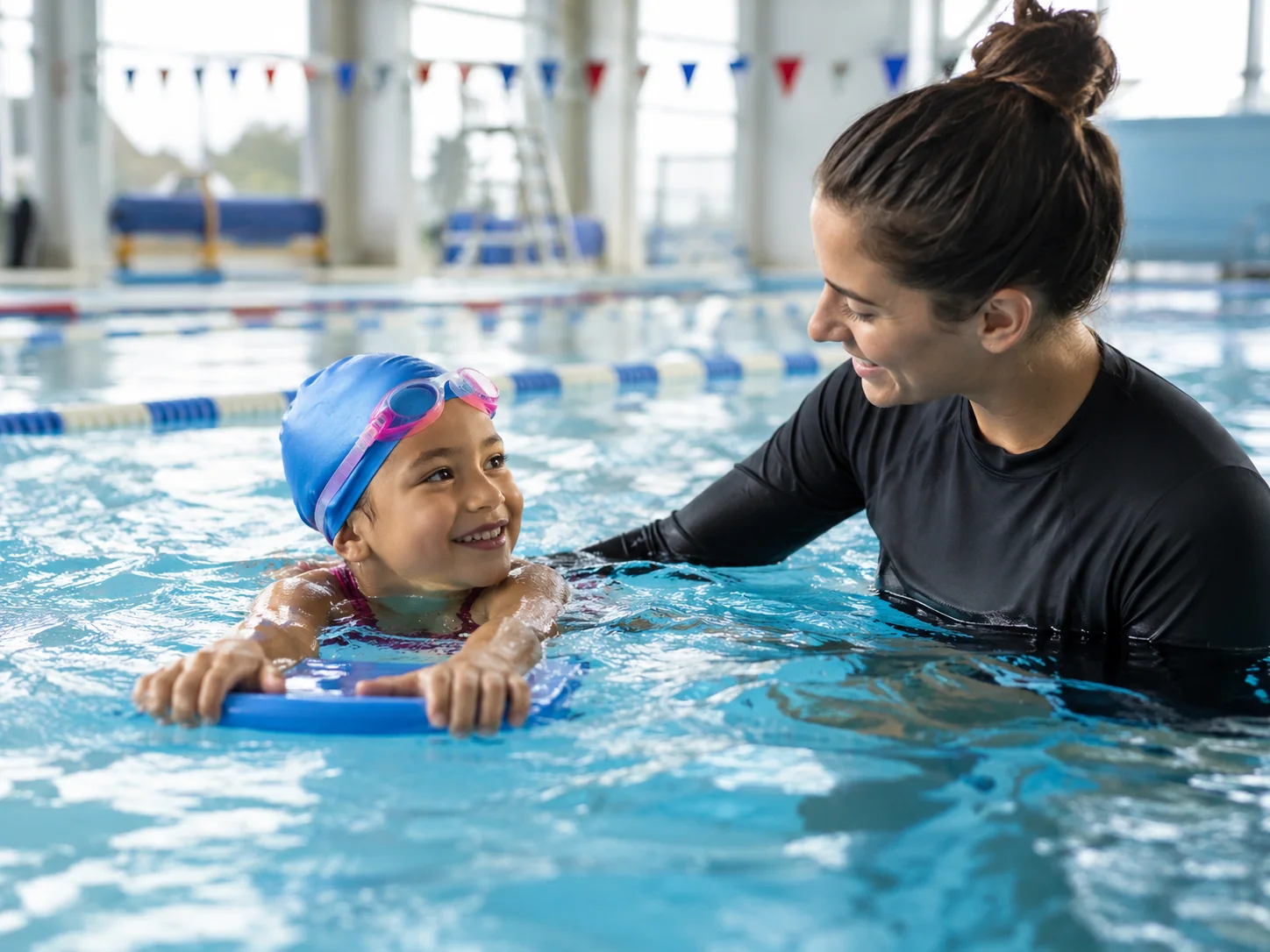 Niña en una clase de natación con supervisión de su entrenadora